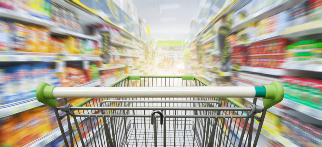 Supermarket aisle with empty green shopping cart
